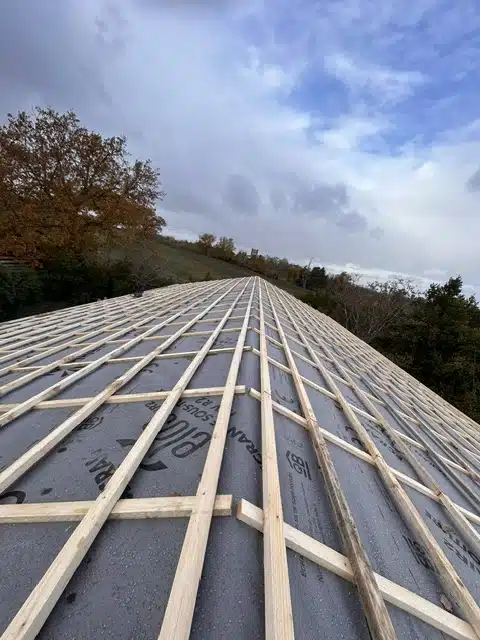 Pose de liteaux sur une toiture en préparation pour l'installation d'une couverture, illustrant les étapes préliminaires d'un travail de couverture de toiture.