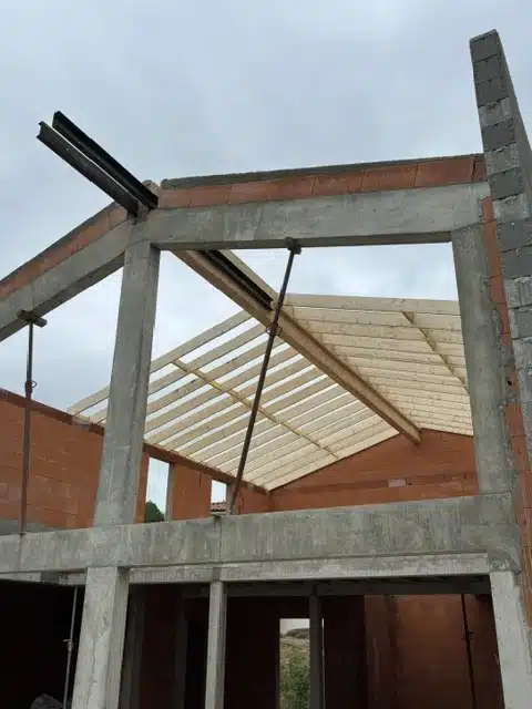 Structure en béton et murs porteurs en cours de construction, mettant en évidence le travail de maçonnerie générale dans l'édification d'une maison individuelle.