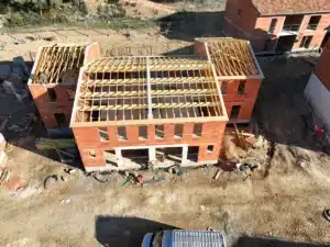 Bâtiment en briques avec charpente en bois, chantier de pose de fermette.