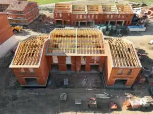 Bâtiment en briques avec charpente en bois, chantier de pose de fermette.