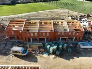 Bâtiment en briques avec charpente en bois, chantier de pose de fermette.